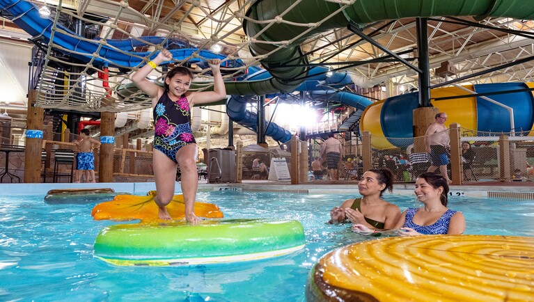 A child balances on a lilly pad at Great Wolf Lodge indoor water park and resort.